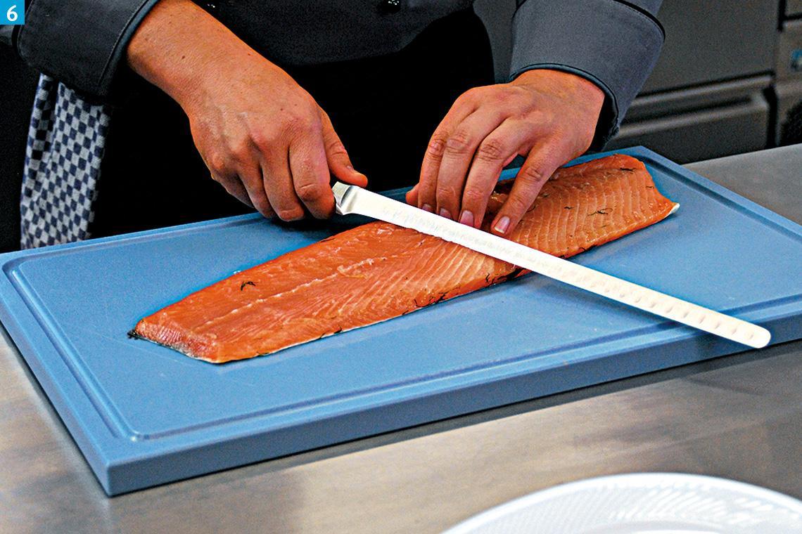 Mit einem speziellen Lachsmesser mit Kullen wird Lachs geschnitten.