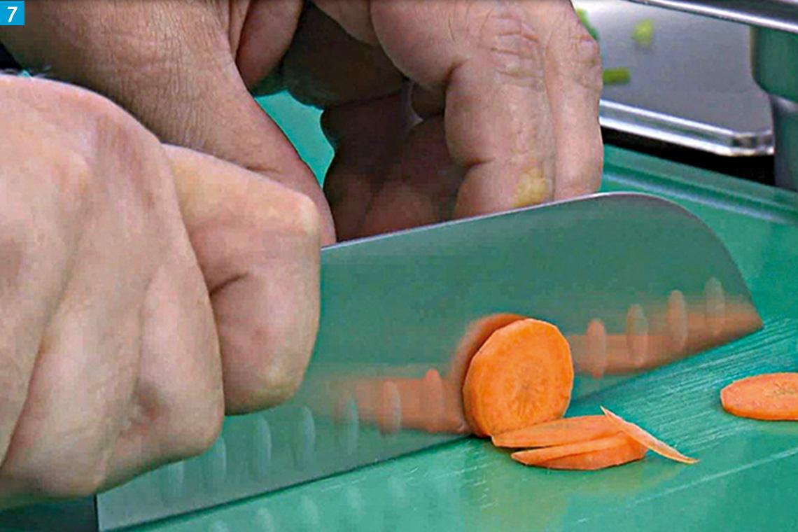Mit einem Santokumesser wird eine Karotte geschnitten.