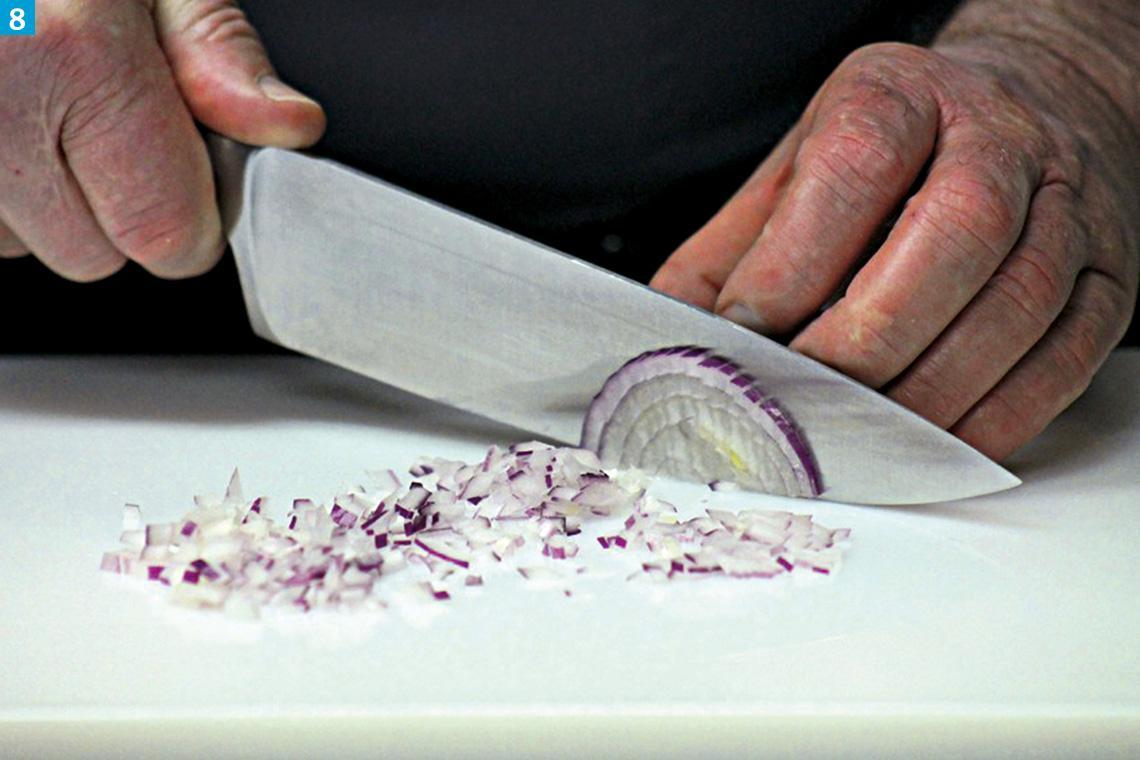 Mit einem großen Messer wird eine Zwiebel geschnitten.