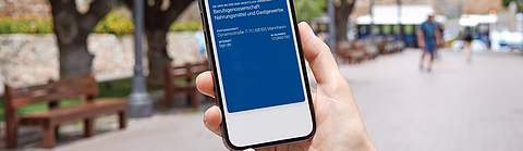 Eine Person hält ein Smartphone mit der digitalen Versichertenkarte der BGN in der Wallet-App in der Hand