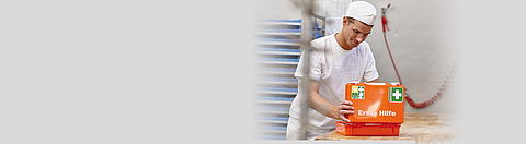 Ein junger Bäcker öffnet einen Erste-Hilfe-Kasten