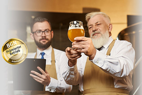 Bierbrauer zeigt einem anderen Bierbrauer ein Glas mit Bier.