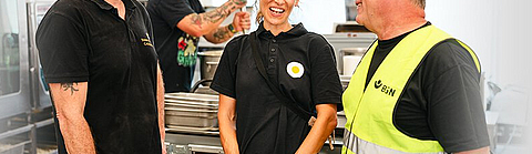 Paul Cusack und Clara Seipp von Sunny Side Catering im Austausch mit BGN-Arbeitsschutzexperte Stephan Thomassohn.