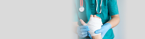 Ärztin oder Arzt hält ein Hand mit Verband.