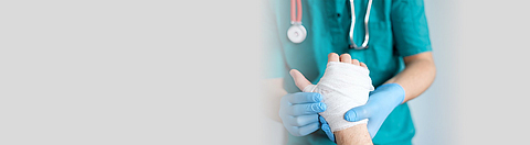 Ärztin oder Arzt hält ein Hand mit Verband.