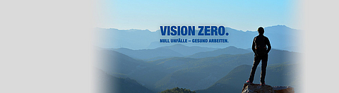 Eine Person steht auf einem Berg und schaut in die Weite. Im Berg ist das Logo für "VISION ZERO".