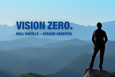 Eine Person steht auf einem Berg und schaut in die Weite. Im Berg ist das Logo für "VISION ZERO".