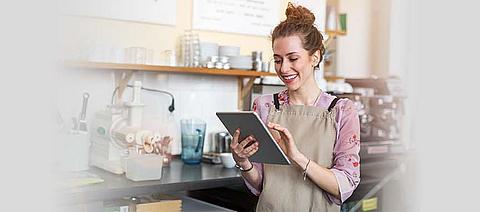 Eine Frau, die in einem Restaurant arbeitet, schaut auf ein Tablet.