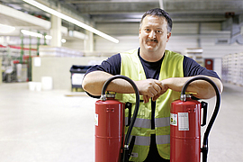 Sicherheitsfachkraft wird mit zwei Feuerlöscher in einer Lagerhalle fotografiert