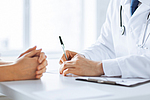 Arzt macht sich Notizen währen eines Patientengesprächs