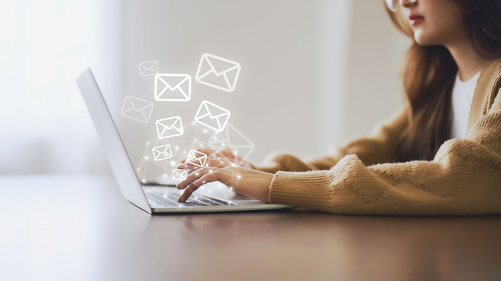 Frau nutzt Laptop und versendet Online-Nachrichten mit E-Mail-Symbol