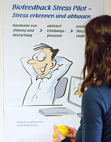 Mitarbeiterin blickt auf ein Plakat zum Thema Stressbewältigung