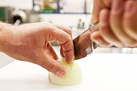 Eine Zwiebel wird mit dem "Krallengriff" geschnitten.