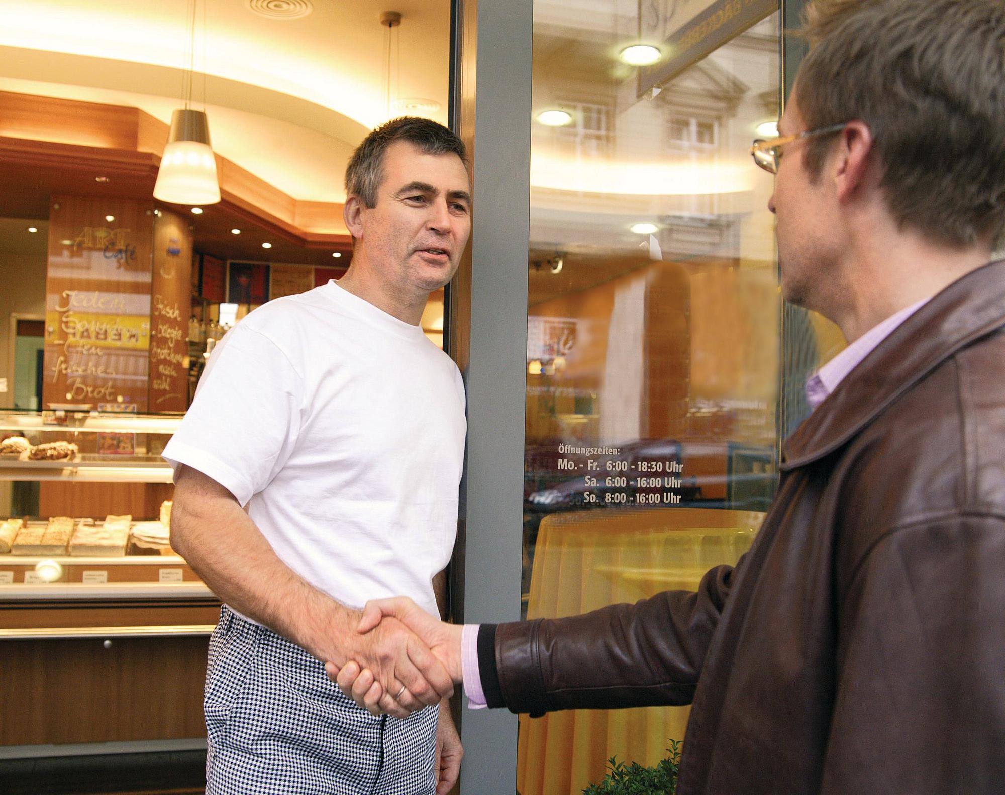 Eine Aufsichtsperson begrüßt den Inhaber einer Bäckerei