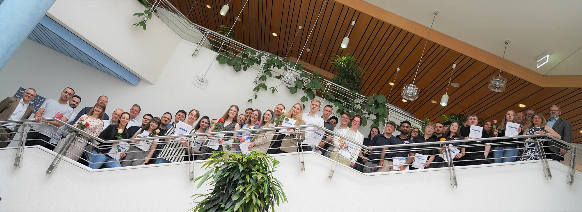 Gruppenfoto der Azubis mit Urkunden auf der Treppe