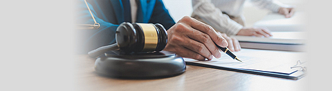 Auf einem Tisch liegen ein Hammer aus dem Gericht und verschiedene Unterlagen.