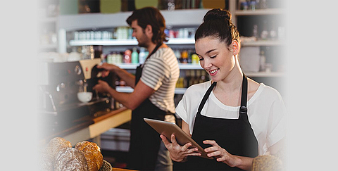 Eine Kellnerin schaut auf Tablet.