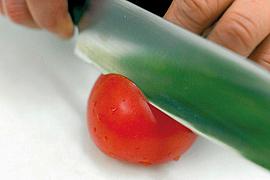 Ein Messer schneidet durch eine Tomate.