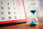 Eine Sanduhr neben einem Monatskalender