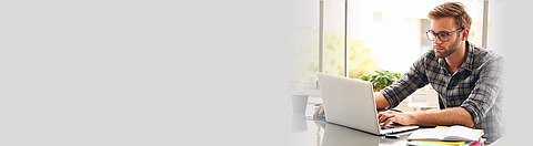 Ein Mann mit Brille sitzt vor einem Laptop.