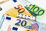 Verschiedene Geldscheine und das Wort Prämie als Buchstabenklötze.
