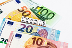 Verschiedene Geldscheine und das Wort Prämie als Buchstabenklötze.
