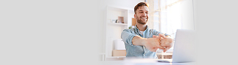 Mann macht Bewegungsübungen vor dem Laptop.