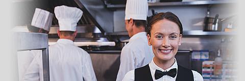 Weibliche Servicekraft steht lächelnd in einer Küche