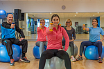 Gruppe trainiert mit Hanteln auf dem Gymnastikball