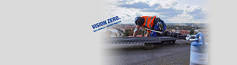 Ein Mann mit Warnweste arbeitet auf einem Dach und ist mehrfach gesichert.