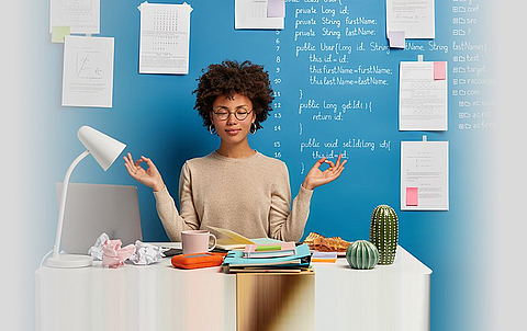 Frau am Arbeitsplatz entspannt sich mit Yoga-Pose