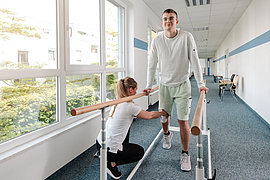Therapeutin hilft jungem Mann in Reha