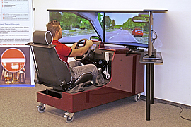 Mann sitzt in ein Fahrsimulator und macht eine Testfahrt