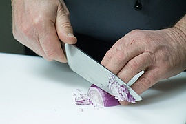 Koch hakt eine halbe rote Zwiebel klein