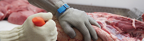 Ausbeinarbeit mit Schnittschutzhandschuh an Messer führender Hand und Stechschutzhandschuh an der anderen Hand