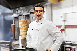 Ein junger Besitzer eines Dönerladens lächelt in die Kamera