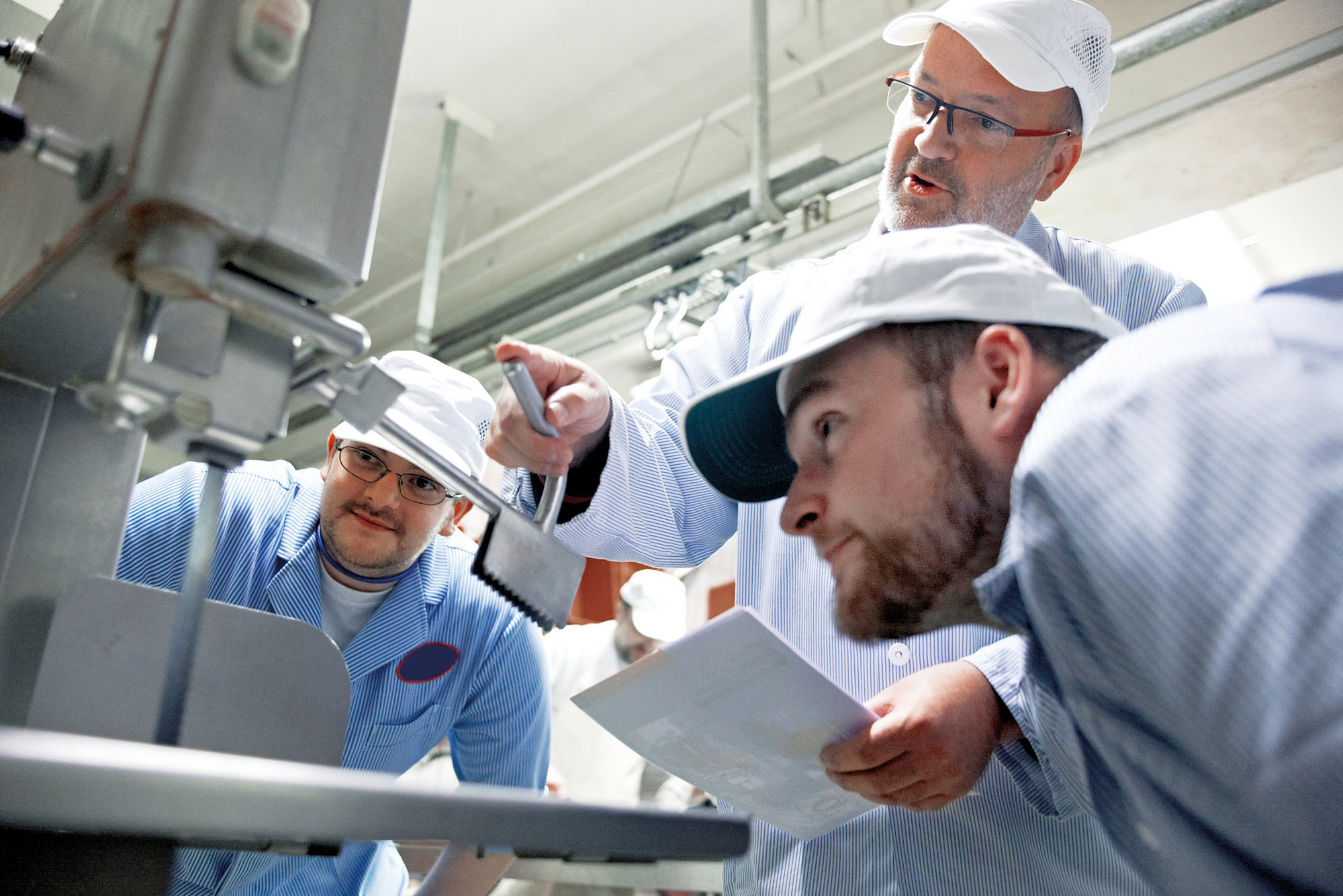 Fachkraft gibt zwei Kollegen eine Unterweisung im Betrieb