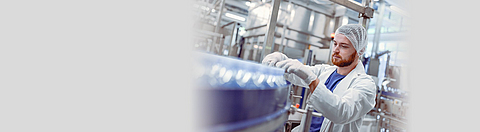 Ein Mitarbeiter prüft ein Laufband mit Plastikflaschen.