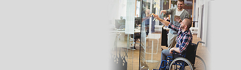 BGN-Integrationspreis - Mannim im Rollstuhl arbeitet mit einem Kollegen an einer Pinwand