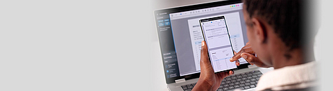 Eine Frau nutzt Software zur elektronischen Rechnungsverarbeitung auf einem Laptop und einem Smartphone