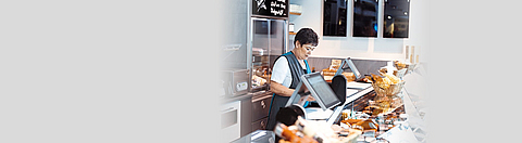 Eine Angestellte steht am Tresen einer Metzgerei und schaut in die Auslage.