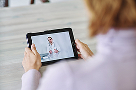 Frau kommuniziert mit Arzt über Tablet